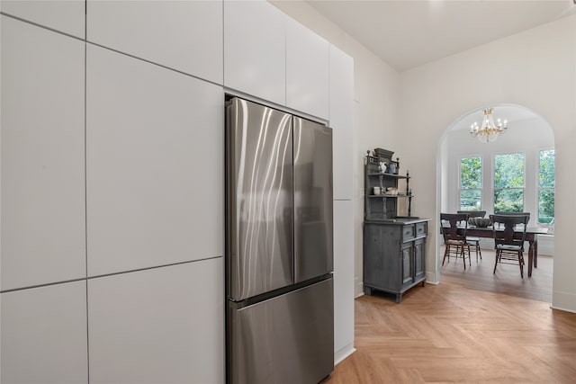 kitchen featuring stainless steel fridge, white cabinetry, light parquet floors, and an inviting chandelier