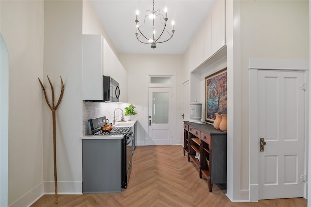 kitchen featuring backsplash, black appliances, an inviting chandelier, white cabinets, and light parquet flooring