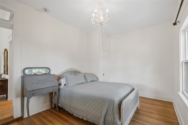 bedroom with an inviting chandelier and light wood-type flooring