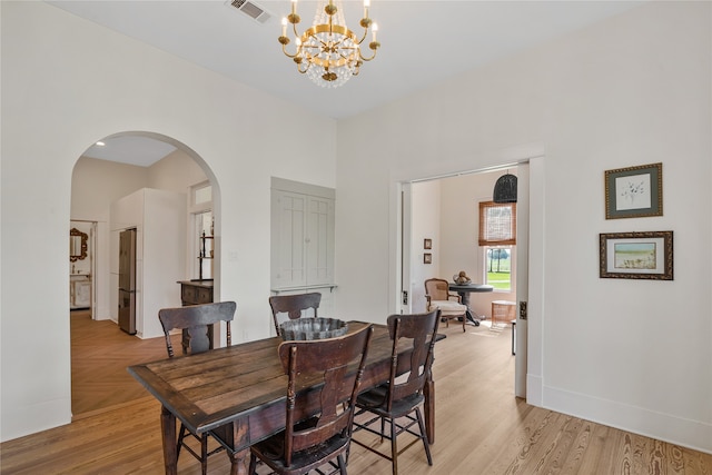 dining room with light hardwood / wood-style flooring and a notable chandelier