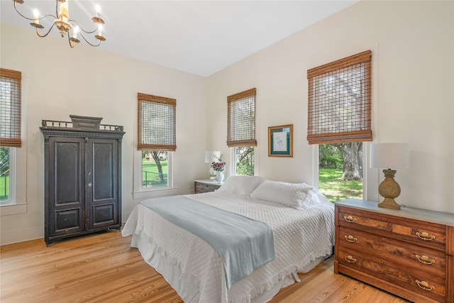 bedroom with light hardwood / wood-style flooring and an inviting chandelier