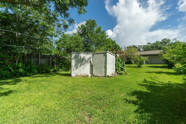 view of yard featuring a storage shed, fence, and an outdoor structure