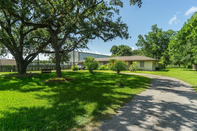 ranch-style house featuring a front yard, driveway, and fence