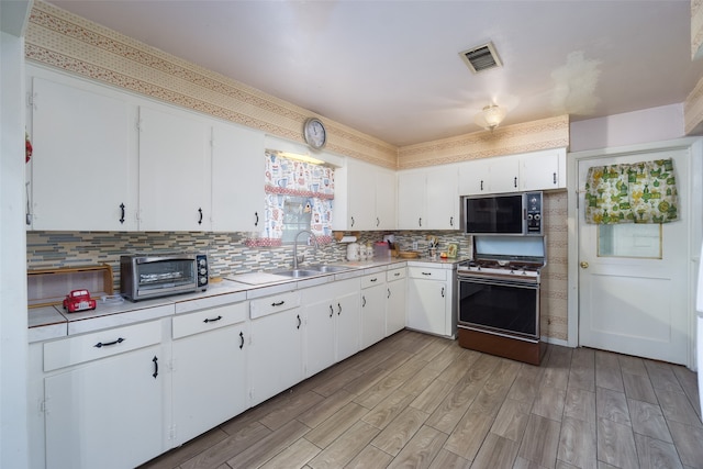 kitchen featuring white range, sink, white cabinetry, and tasteful backsplash