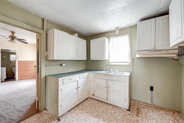 kitchen featuring ceiling fan, light carpet, custom exhaust hood, sink, and white cabinetry