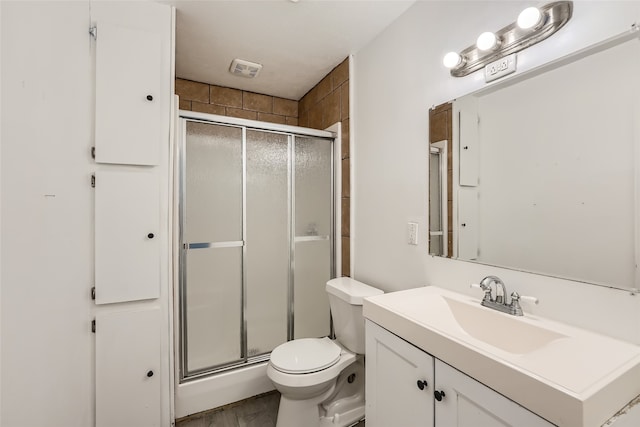 bathroom featuring vanity, toilet, and a shower with shower door