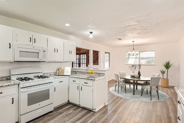 kitchen featuring white cabinetry, hardwood / wood-style floors, a chandelier, and white appliances