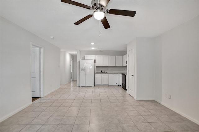 kitchen with light tile patterned floors, white cabinets, white refrigerator with ice dispenser, and range