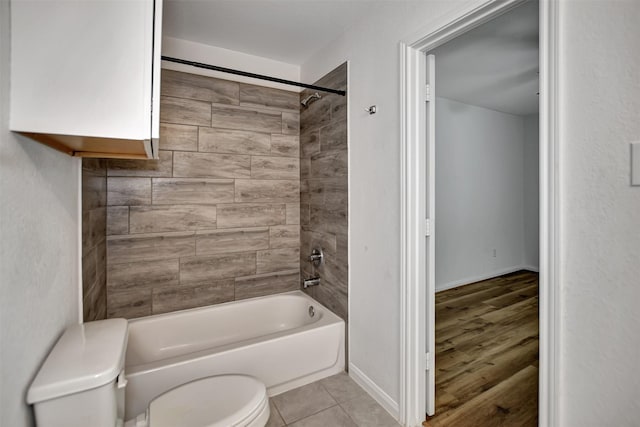 bathroom featuring tiled shower / bath combo, toilet, and tile patterned flooring