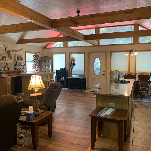 living room with sink, vaulted ceiling with beams, a notable chandelier, a textured ceiling, and hardwood / wood-style flooring