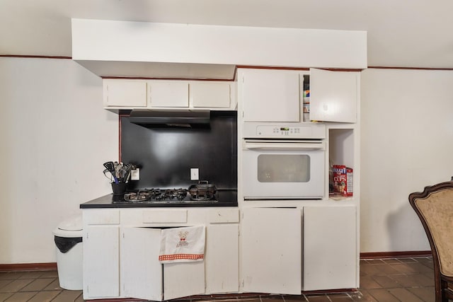 kitchen with white oven, dark countertops, white cabinets, black gas stovetop, and under cabinet range hood