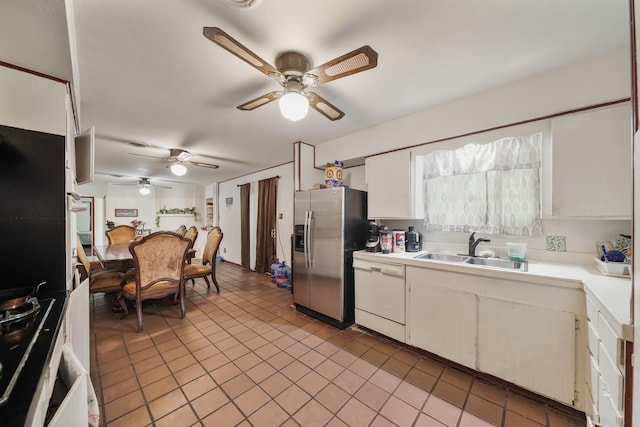 kitchen featuring white dishwasher, a sink, white cabinets, light countertops, and stainless steel fridge