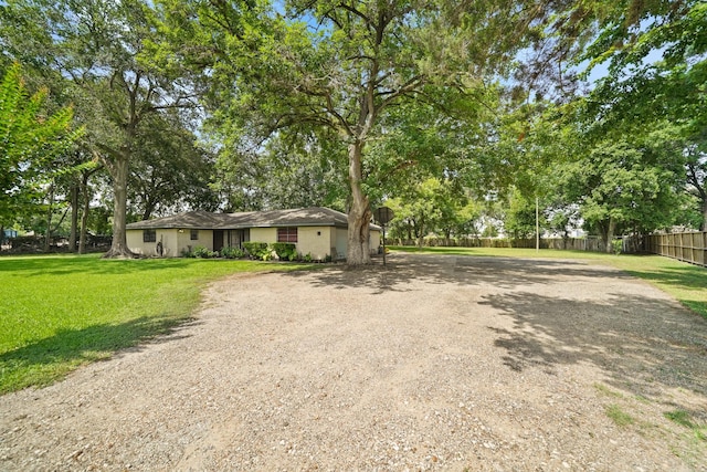 view of front facade featuring driveway, a front yard, and fence