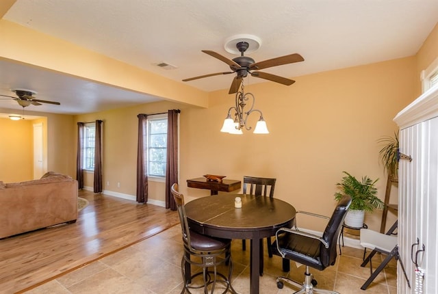 dining room with ceiling fan with notable chandelier and light tile floors