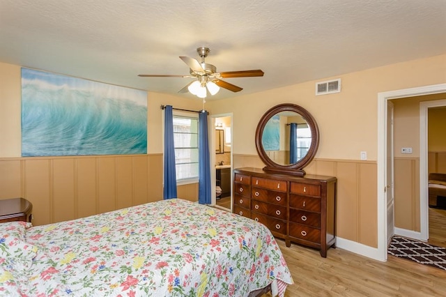 bedroom featuring hardwood / wood-style flooring, ensuite bathroom, and ceiling fan