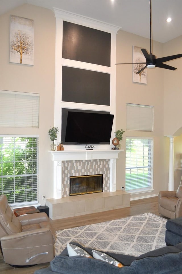 living room with a fireplace, a high ceiling, ceiling fan, and hardwood / wood-style floors