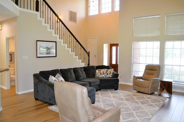 living room featuring plenty of natural light, wood-type flooring, and a high ceiling