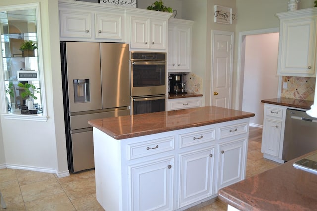 kitchen featuring tasteful backsplash, white cabinets, a kitchen island, and appliances with stainless steel finishes