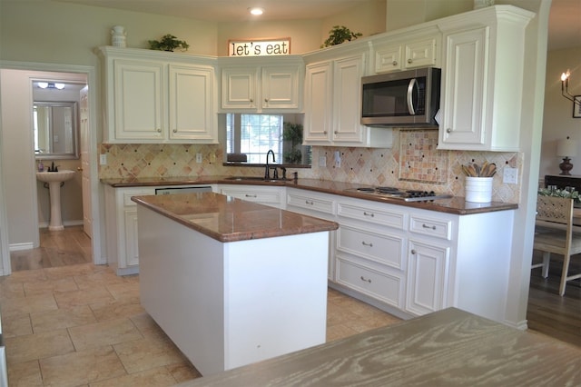 kitchen featuring sink, stainless steel appliances, a kitchen island, dark stone countertops, and white cabinets