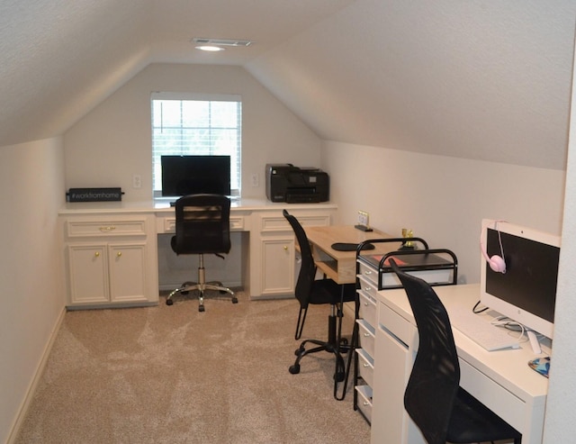 office with a textured ceiling, light carpet, built in desk, and vaulted ceiling