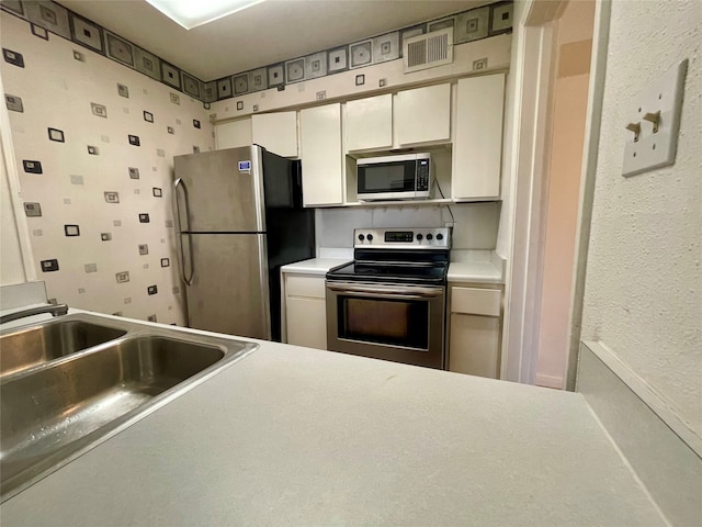 kitchen featuring appliances with stainless steel finishes, white cabinetry, and sink