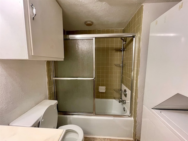 full bathroom with vanity, a textured ceiling, toilet, and bath / shower combo with glass door