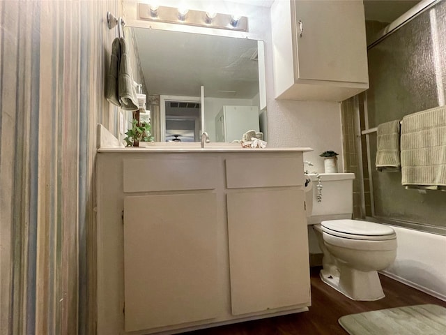 full bathroom featuring vanity, toilet, wood-type flooring, and bath / shower combo with glass door