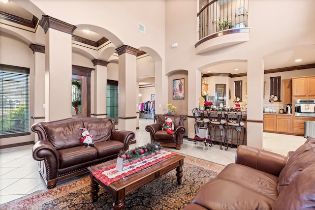 tiled living room featuring a high ceiling, ornamental molding, and ornate columns