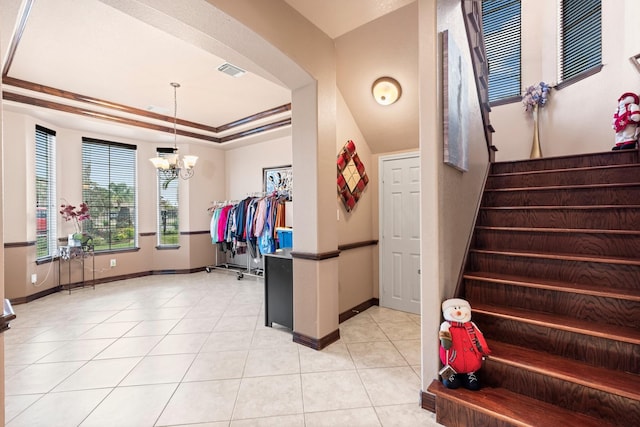 interior space featuring crown molding, an inviting chandelier, light tile patterned floors, and a raised ceiling