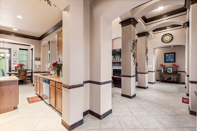 interior space featuring sink, ornamental molding, light tile patterned flooring, decorative columns, and stainless steel dishwasher