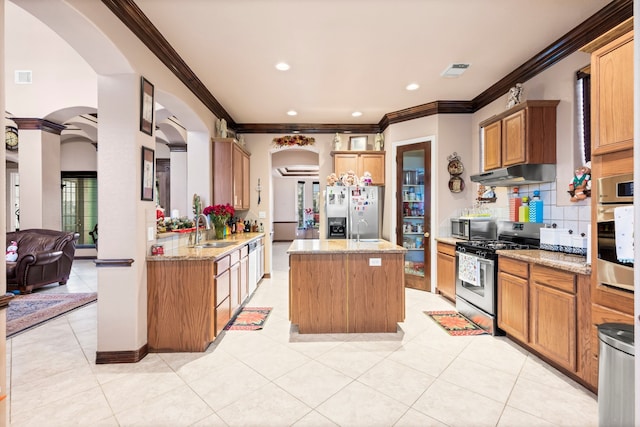 kitchen with appliances with stainless steel finishes, a kitchen island, tasteful backsplash, sink, and light stone counters