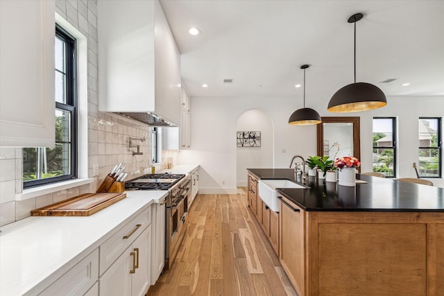 kitchen featuring custom exhaust hood, white cabinets, sink, and pendant lighting