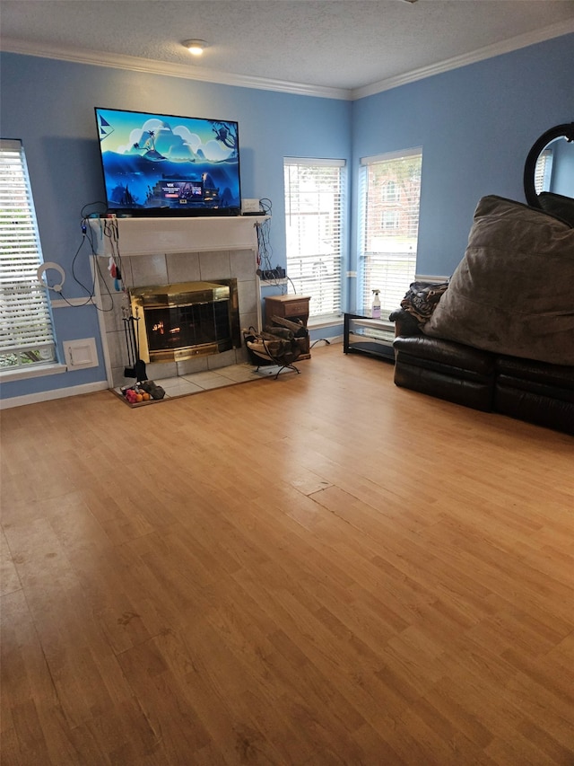 living room featuring a healthy amount of sunlight, a tiled fireplace, and light wood-type flooring