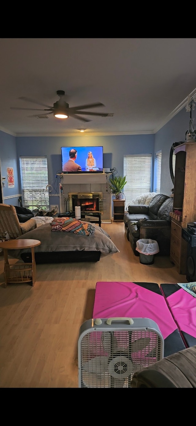 living room featuring a fireplace, ceiling fan, wood-type flooring, and ornamental molding