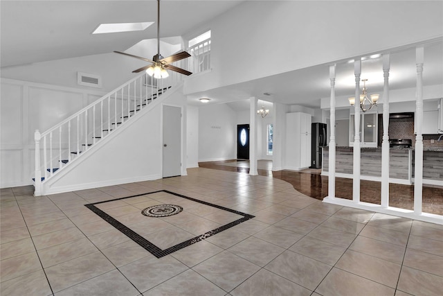 interior space featuring a healthy amount of sunlight, a skylight, ceiling fan with notable chandelier, and light tile patterned floors