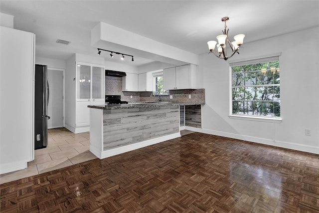 kitchen with white cabinetry, range, kitchen peninsula, and backsplash