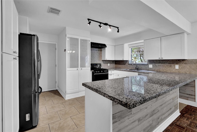 kitchen with white cabinetry, stainless steel fridge, a kitchen breakfast bar, kitchen peninsula, and black range with gas cooktop