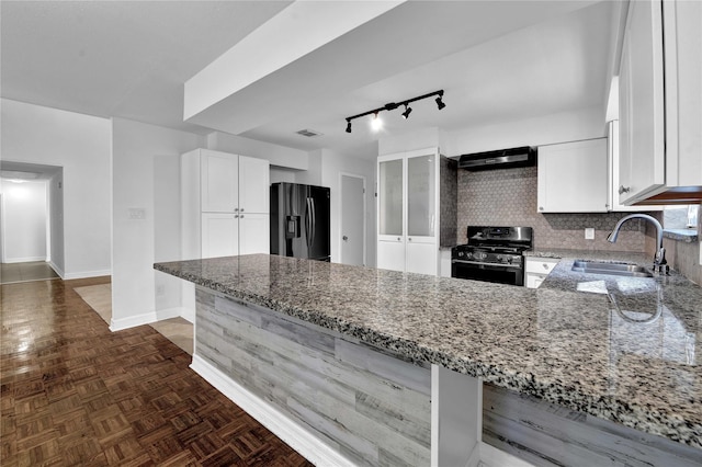 kitchen with light stone countertops, stainless steel range with gas cooktop, white cabinets, and black refrigerator with ice dispenser