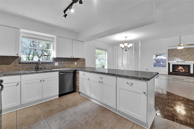 kitchen featuring dishwasher, a large fireplace, sink, white cabinets, and backsplash