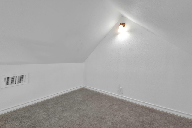 additional living space featuring vaulted ceiling and carpet floors