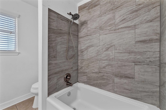 bathroom with tiled shower / bath combo, tile patterned floors, and toilet