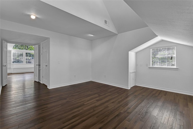 bonus room featuring dark wood-type flooring, lofted ceiling, and plenty of natural light