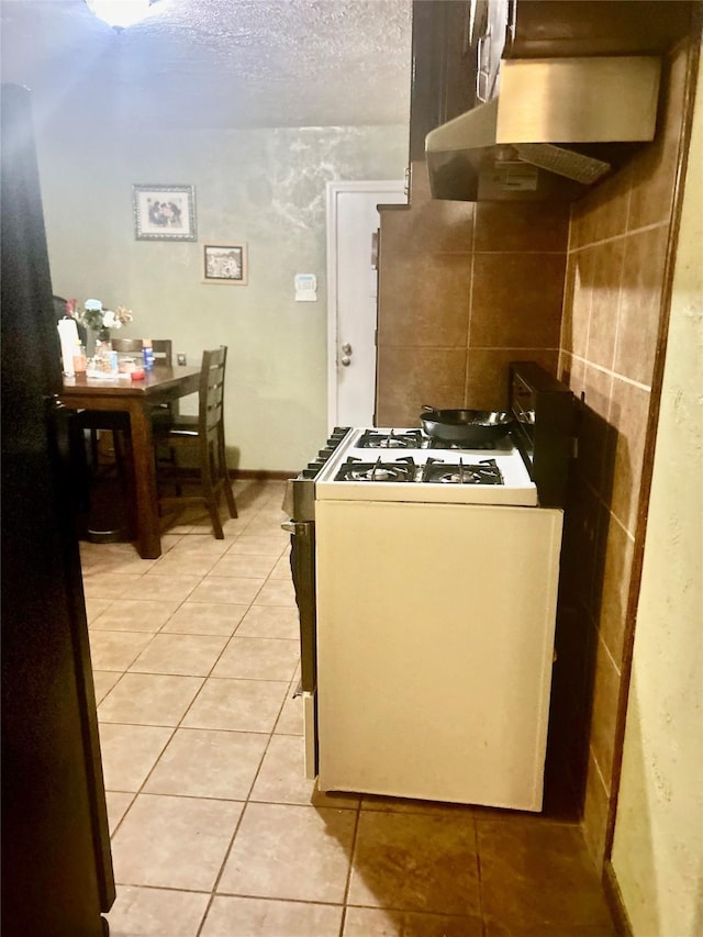 kitchen with light tile patterned flooring, white gas range, and a textured ceiling