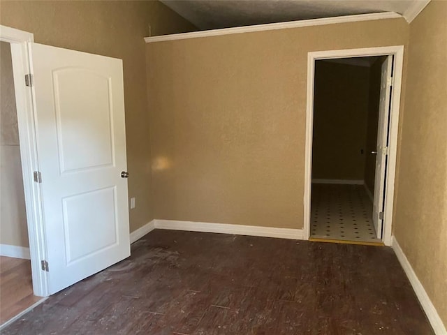 spare room with dark hardwood / wood-style flooring, ornamental molding, and vaulted ceiling