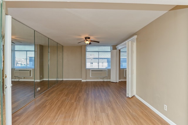 interior space with ceiling fan, wood-type flooring, and a wall mounted air conditioner