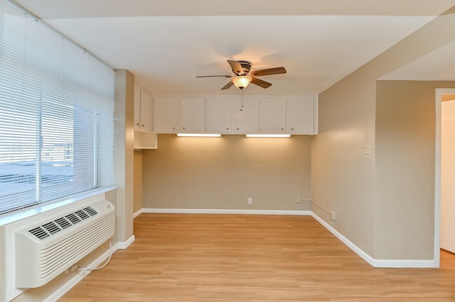 empty room with ceiling fan, light hardwood / wood-style floors, and a wall mounted AC