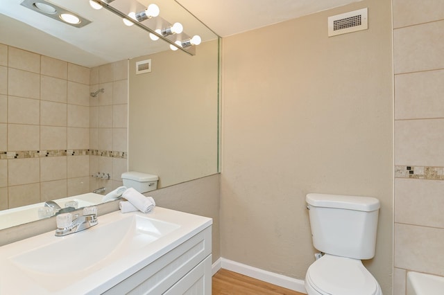 full bathroom featuring vanity, toilet, wood-type flooring, and tiled shower / bath combo