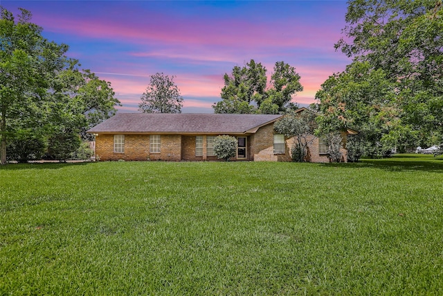 view of front facade with a lawn and brick siding