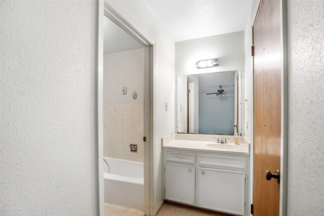 bathroom featuring ceiling fan, vanity, and a bath