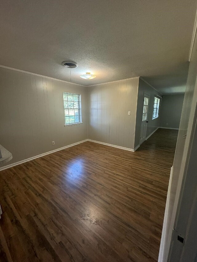 spare room featuring dark hardwood / wood-style flooring, a textured ceiling, and ornamental molding